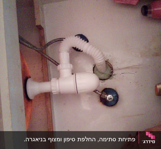 צינור ניקוז לבן מתחת לכיור עם חיבורים